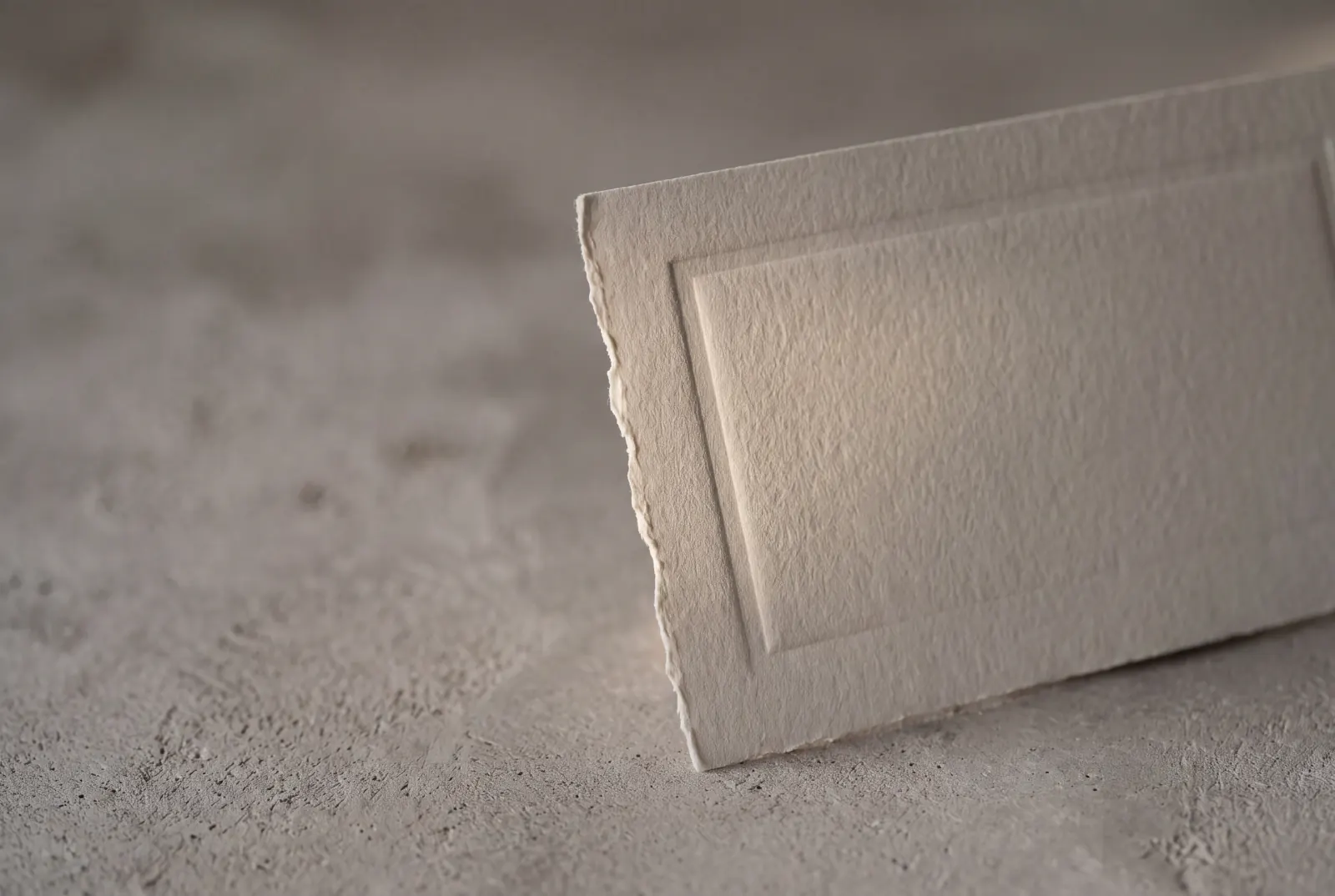 A letterpressed cotton-rag card, deckle edge left raw