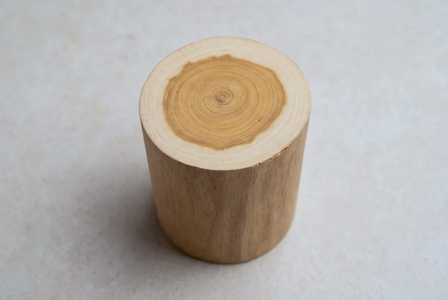 A cut billet of sandalwood standing on end, pale sapwood ringing a darker honey-coloured heartwood core