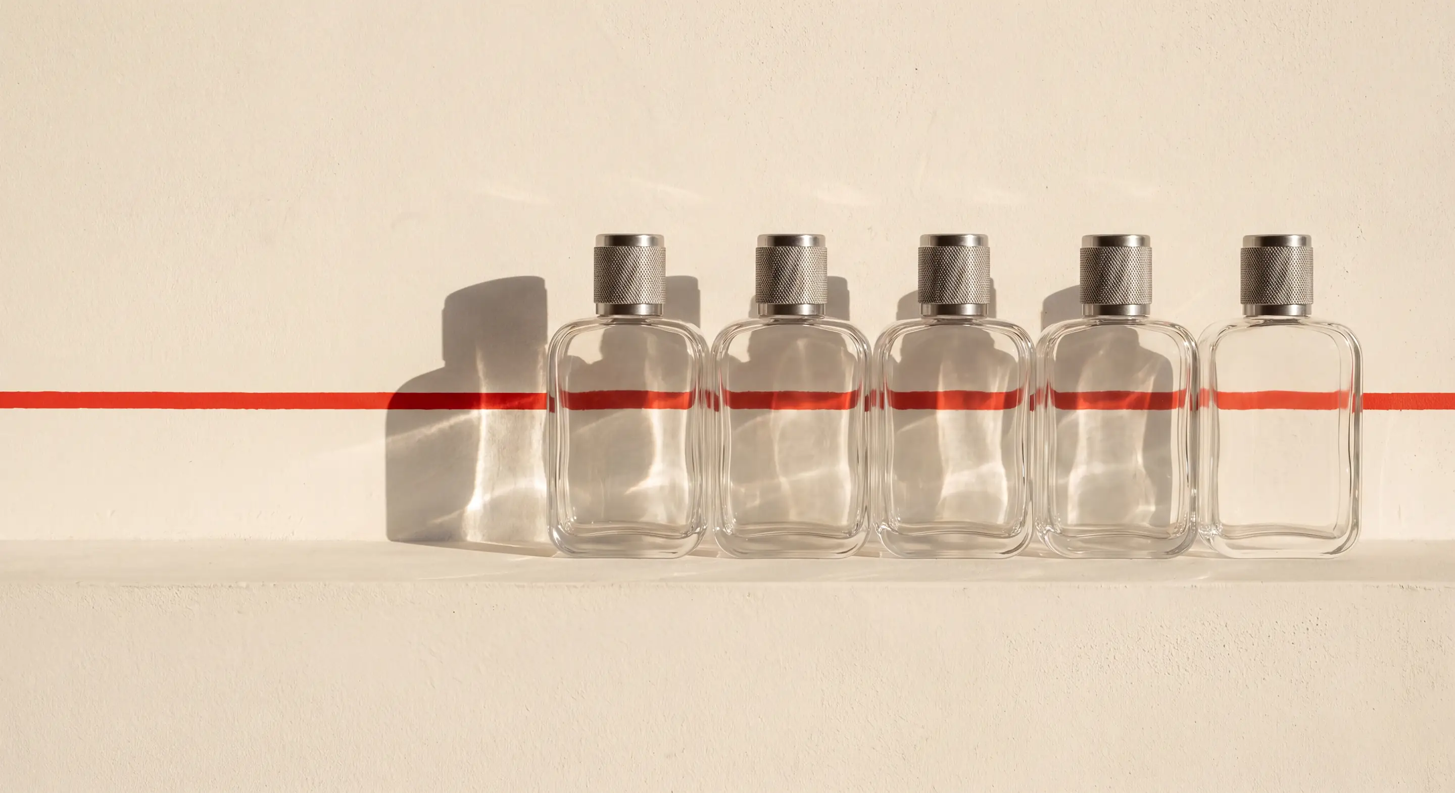 The five flasks in a row on a plaster ledge, one painted red line running across the wall and through every band