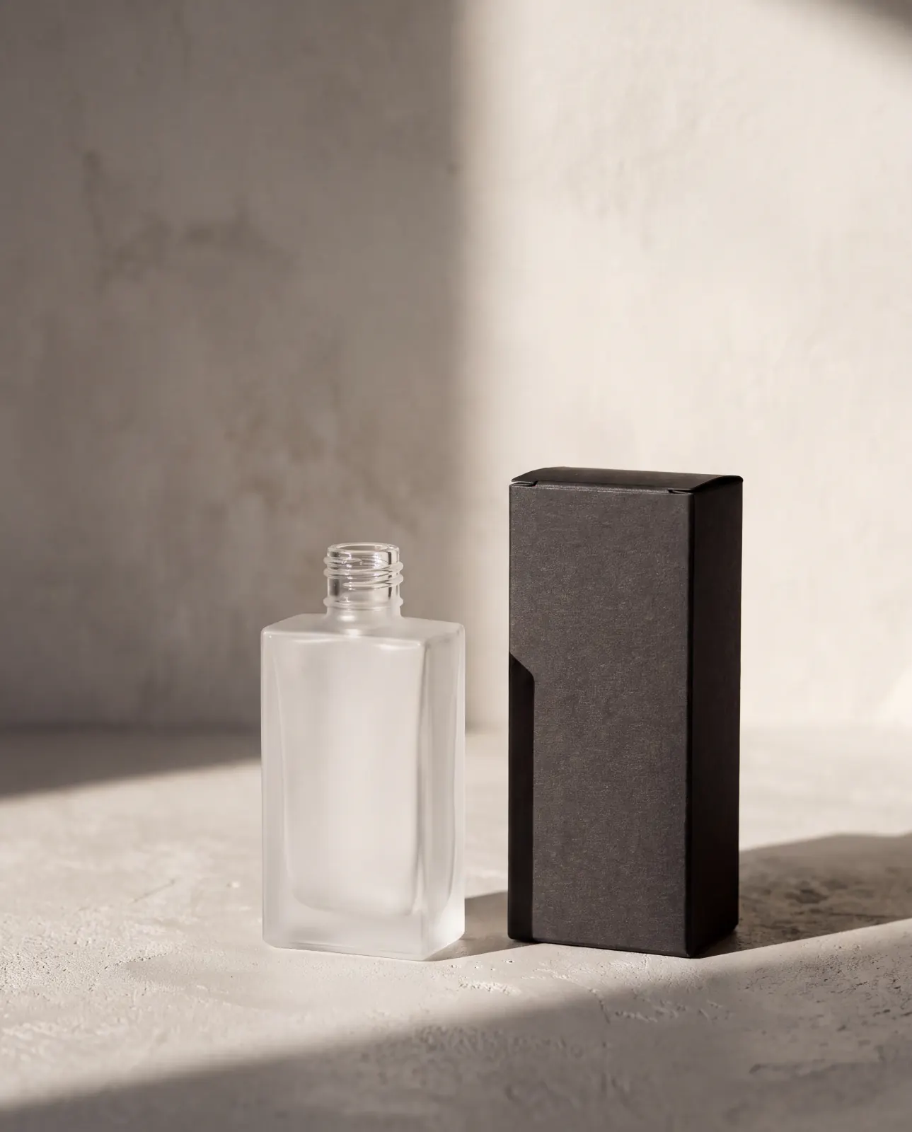 A bottle beside its carton, on concrete